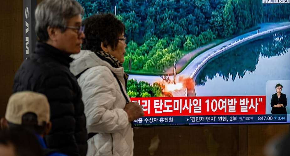 People walk past a screen showing news coverage with file footage of a North Korean missile launch at Seoul Station on October 29. -  Philip Fong, AFP