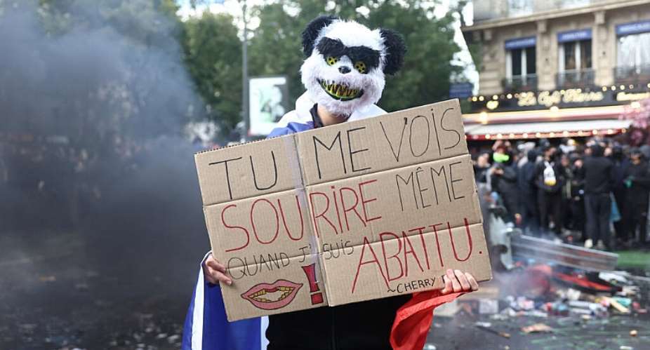 A masked protester in central Paris holds a placard reading You see me smiling even when Im down amid clashes on the sidelines of nationwide protests on October 17, 2026. -  Abdul Saboor, Reuters