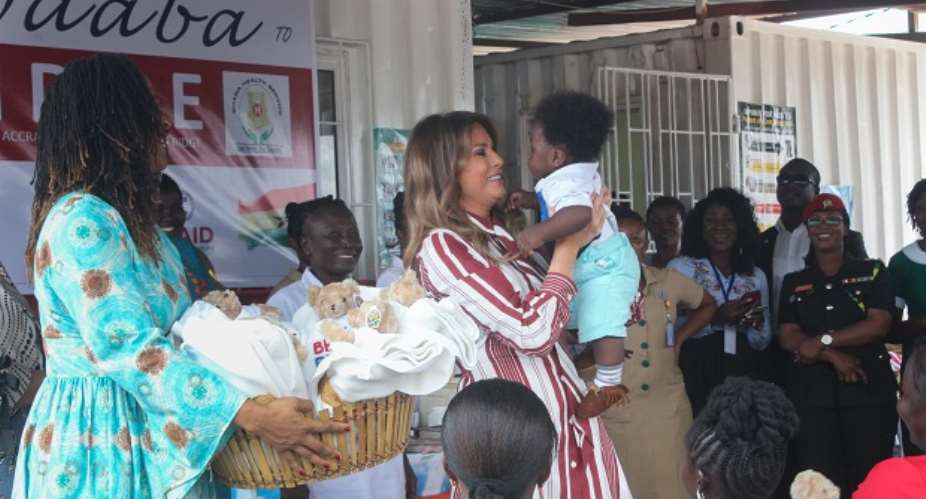 Mrs. Melania Trump holding a baby at the child welfare clinic during her visit