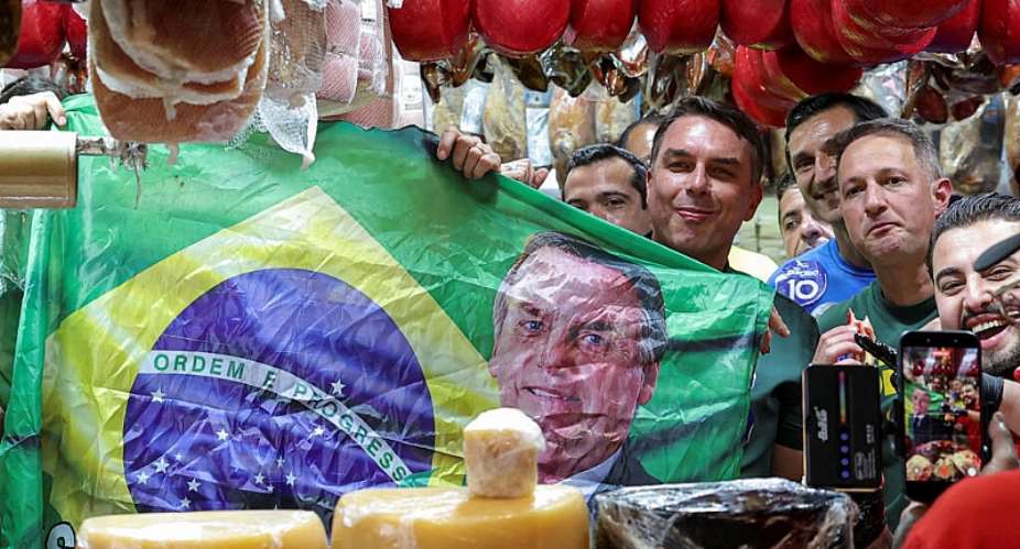 Brazilian presidential candidate Flavio Bolsonaro holds a Brazilian flag depicting his father, former president Jair Bolsonaro, at a campaign rally in Sao Paulo on September 28, 2026. -  Amanda Perobelli, Reuters