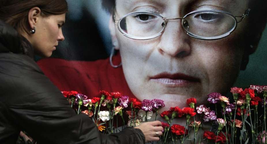 A file image taken on October 7, 2009 of a woman placing flowers before a portrait of slain Russian journalist Anna Politkovskaya in Moscow. -  Pavel Golovkin, AP