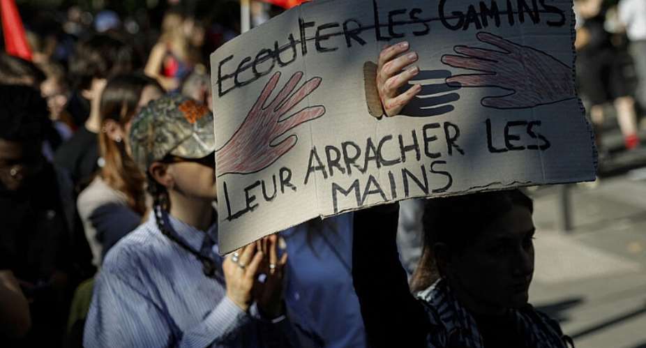 A demonstrator holds a placard with the phrase, Listen to the kids crossed out and underneath: Tear their hands off – likely a reference to a protester who lost a hand to a stun grenade – in Paris. -  Geoffroy ven der Hasselt, AFP -  Geoffroy ven der Hasselt, AFP