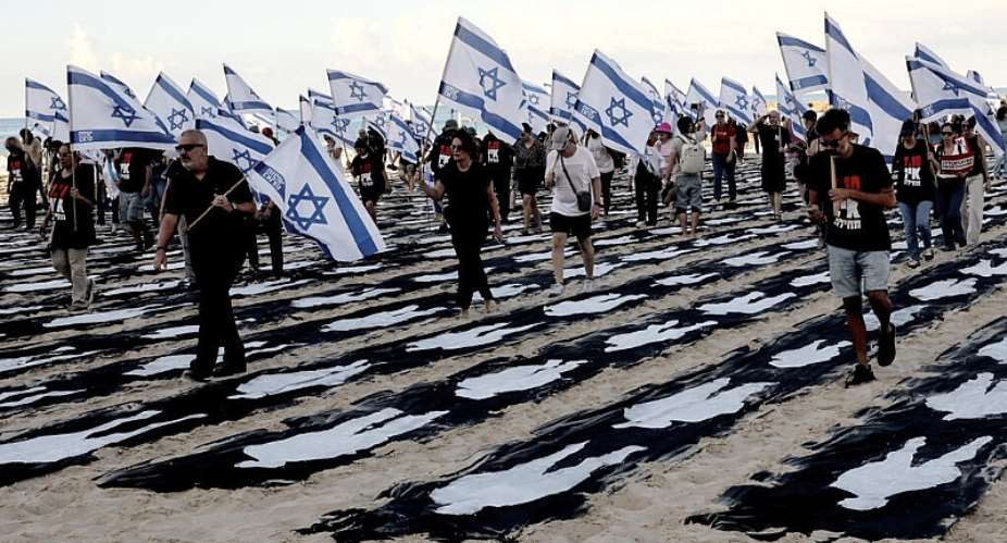 People carrying Israeli flags walk through a commemorative installation set up on the beach in Tel Aviv to mark the third anniversary of Hamass October 7 attack on Israel. -  AFP
