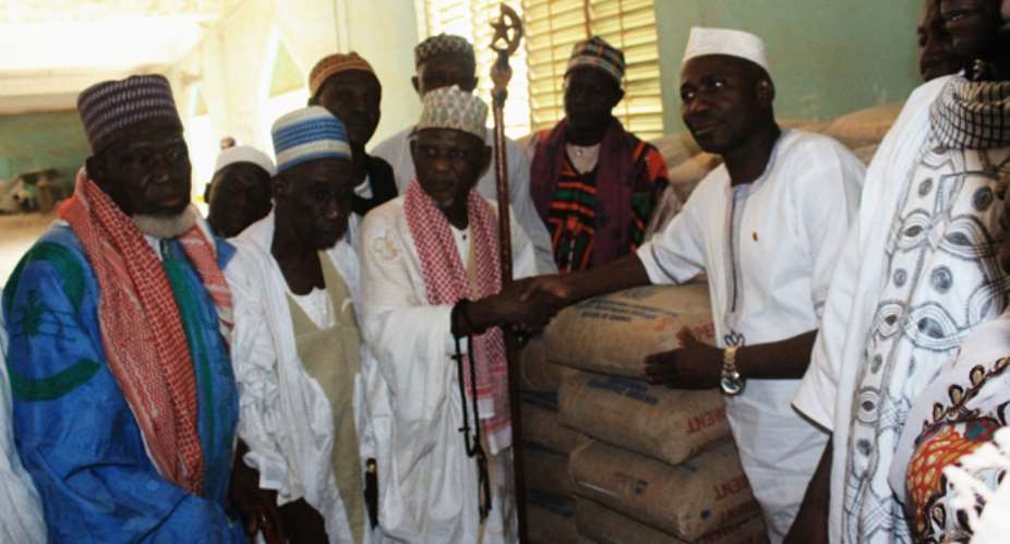 Frank Fuseini presenting bags of cement to the Chief Imam