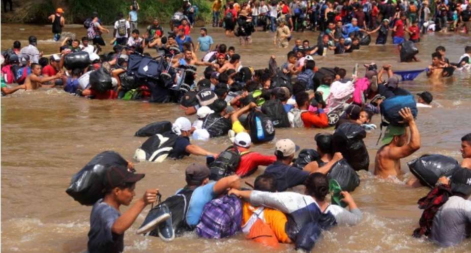 A group of migrants cross the river Suchiate connecting Guatemala and Mexico: The refugee caravan is still thousands of miles from the US border
