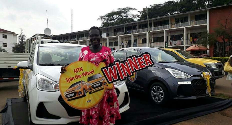 Evelyn Afua Owusuaa, basic school teacher at Afrancho DA School standing behind the car she won in the MTN spin the wheel promotion