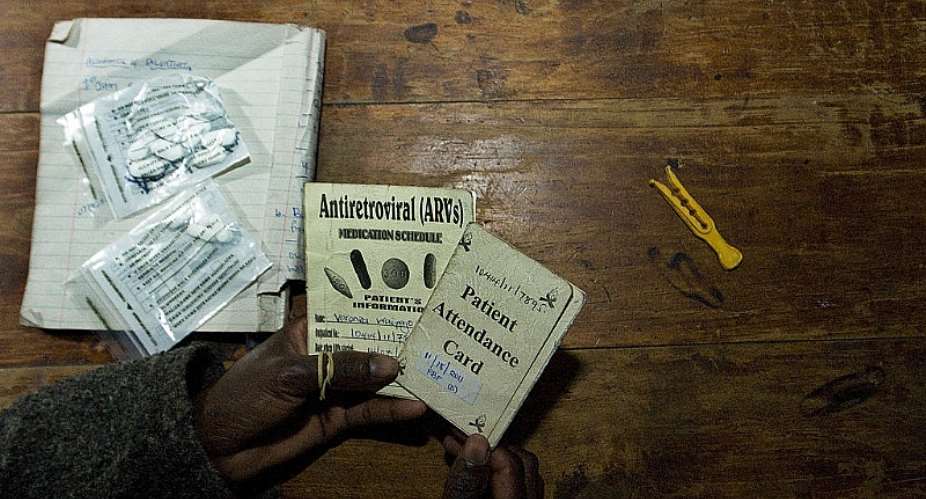 A person living with HIV shows her clinic appointment and anti-retroviral drugs regimen card.  - Source: TONY KARUMBAAFPGettyImages