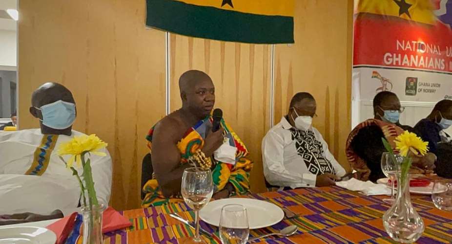 Nana Kota Ntiamoah with microphone dressed in cloth speaking during the inauguration of the NUGN in Bergen. Seated with him are the Ghana's Ambassador to Norway, Jennifer Lartey and her team from the Ghana Embassy, Oslo