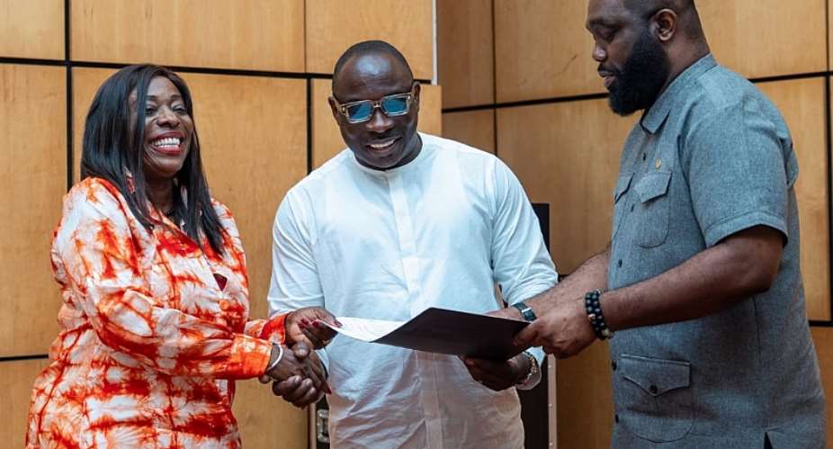 Catherine AFEKU receives her appointment letter from Ghanas representative of WTFI, Mr Richard Owusu (middle)