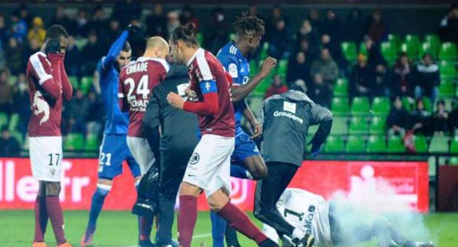 Metz and Lyon players react after firecrackers exploded