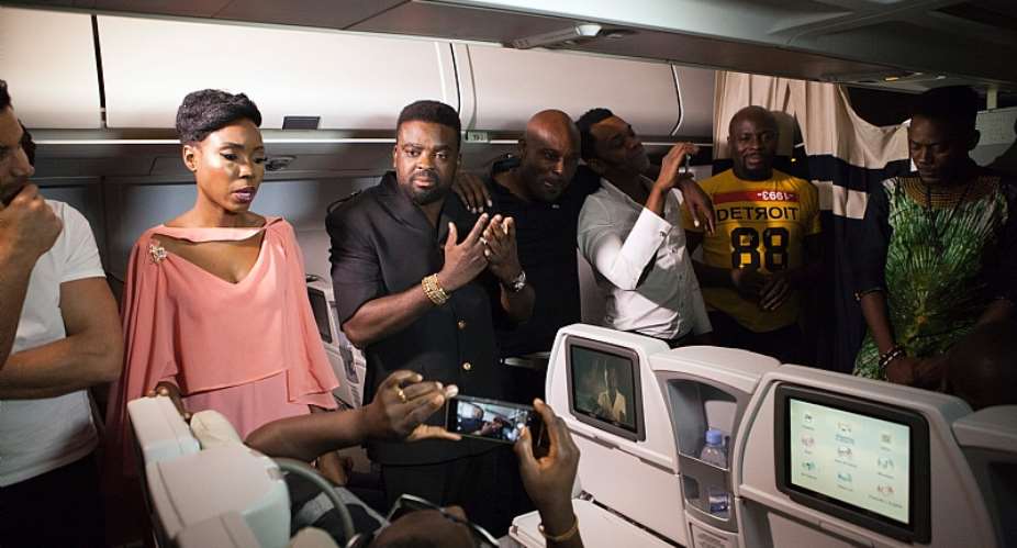 Nigerian director Kunle Afolayan speaks with passengers aboard a flight during the premiere of his film, The CEO. - Source: Florian PlacheurAFPGetty