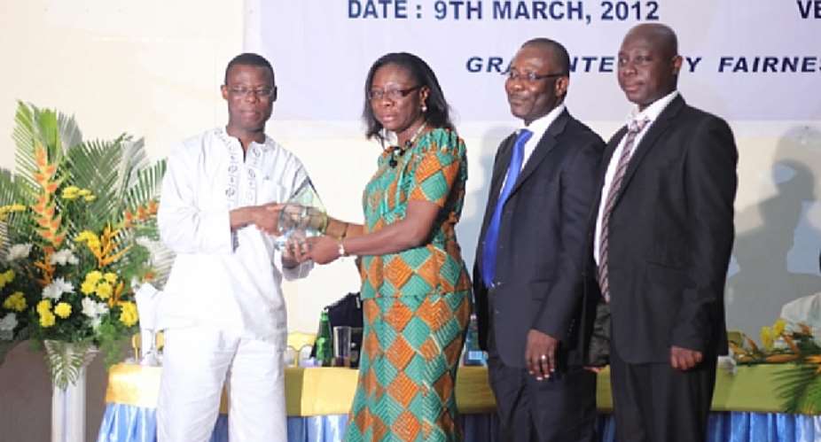 Adiki O. Ayitevie, Director, External Affairs  Communications at Newmont Ghana receiving the award from the Deputy Minister of Finance and Economic Planning, Fifi Kwetey.