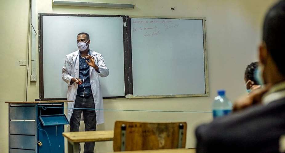 A teacher in Ethiopia wears a face mask and stands behind a blue thread-line denoting a boundary between him and the students. - Source: Photo by AMANUEL SILESHI/AFP via Getty Images