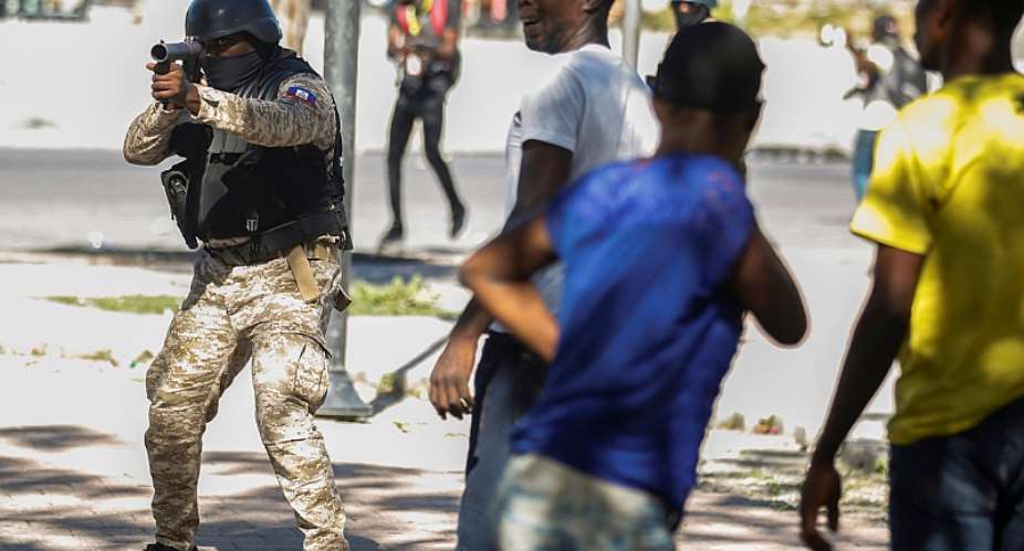 A police officer aims at demonstrators during protests in Port-au-Prince, Haiti, on February 8, 2021. Two journalists were shot while covering those protests. ReutersJeanty Junior Augustin