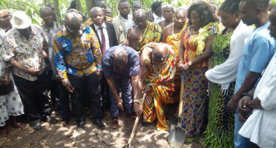 Catherine Afeku cutting the sod flanked by