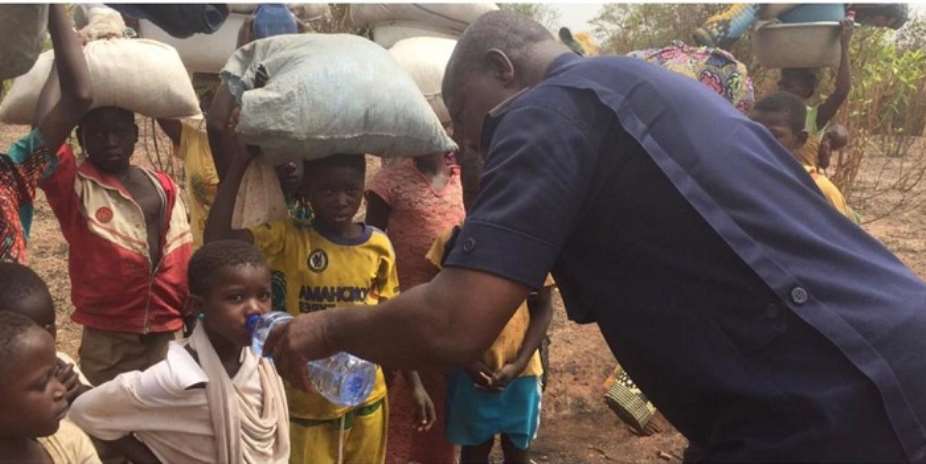 Chereponi District Police Commander, ASP Henry Amankwah Tia providing water to thisty children fleeing the community.