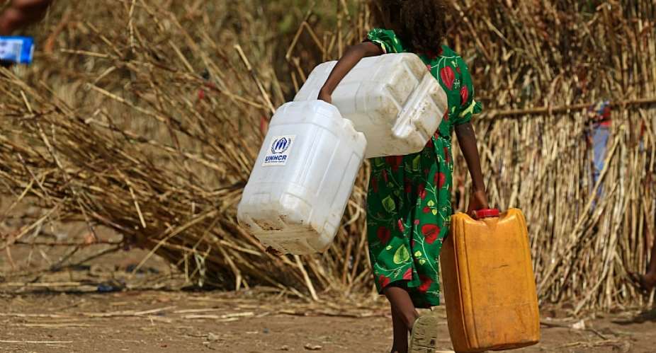 A young Ethiopian refugee carries water containers at the Um Raquba camp in Sudan in November 2020.  - Source: Ashraf ShazlyAFP via Getty Images