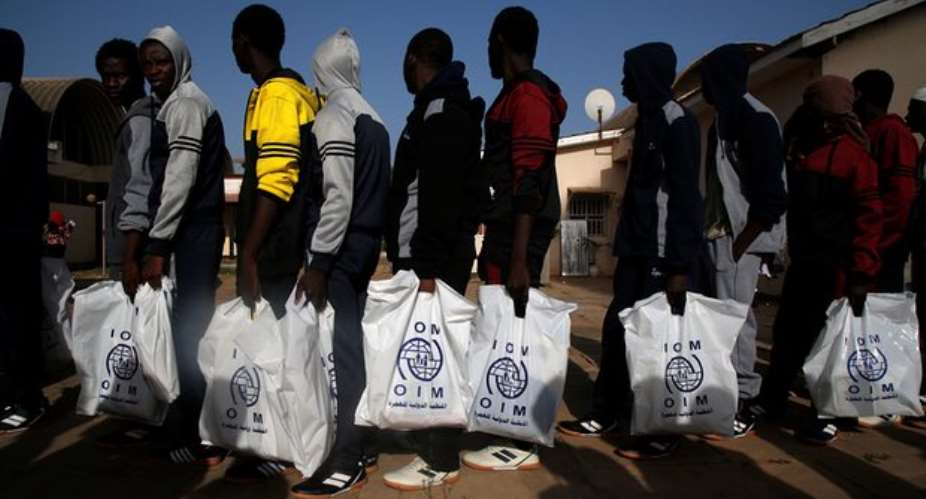 Gambian migrants returning home from Libya carry bags from UN agency the International Organization for Migration. Photograph: Luc GnagoReuters