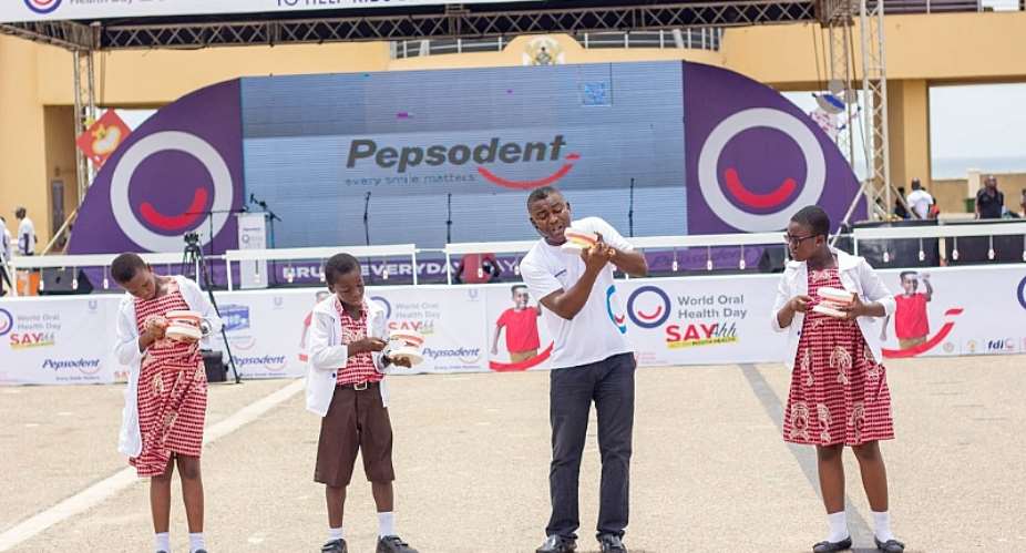 Some kids and an official of Unilever demonstrate teeth brushing skills