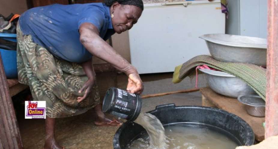 A flood victim scoops water from her house.