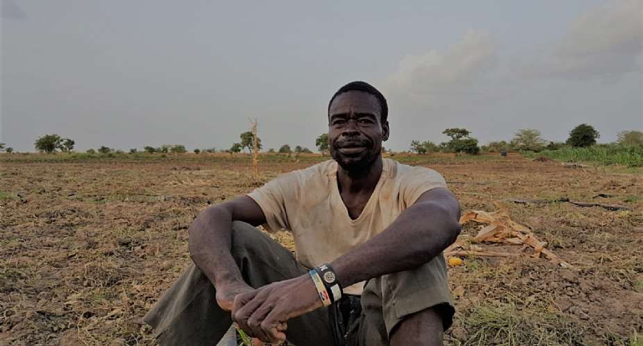 A Ghanaian vegetable farmer sits on his land - Source: