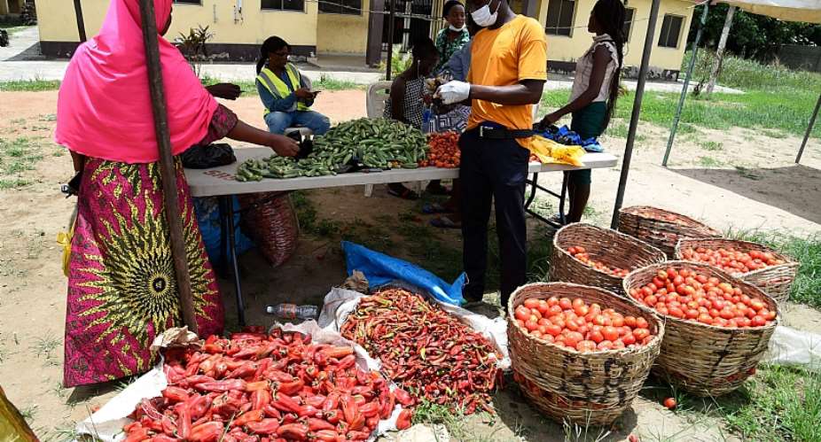 A tomato vendor attends to buyer at a makeshift food market established to cushion the effect of COVID lockdown in Lagos. - Source: Photo by Pius Utomi EkpeiAFP via Getty Images