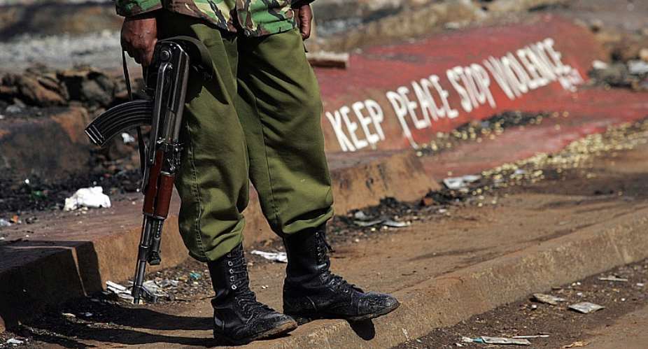 A Kenyan policeman stands next to a painted sign reading "keep peace stop violence" during protests in Nairobi in 2008.  - Source: Roberto Schmidt/AFP via Getty Images