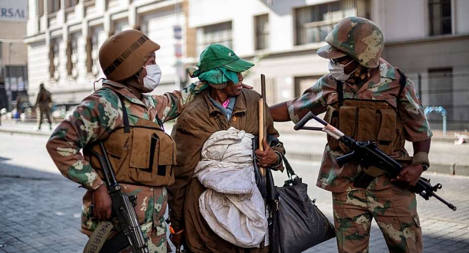 Soldiers escort a homeless woman to a gathering point in the Johannesburg CBD during the nationwide Covid-19 lockdown.  - Source: Michele SpatariAFP-GettyImages