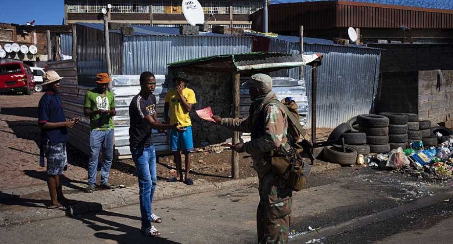 A member of the South African National Defence Force hands out pamphlets informing township residents about COVID-19 in Johannesburg.  - Source: Kim LudbrookEPA-EFE