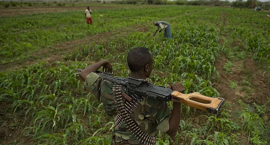 A soldier looking over a maize field where Somali farmers are tending a crop in Dollow, northern Somalia.  - Source: TONY KARUMBA/AFP/GettyImages