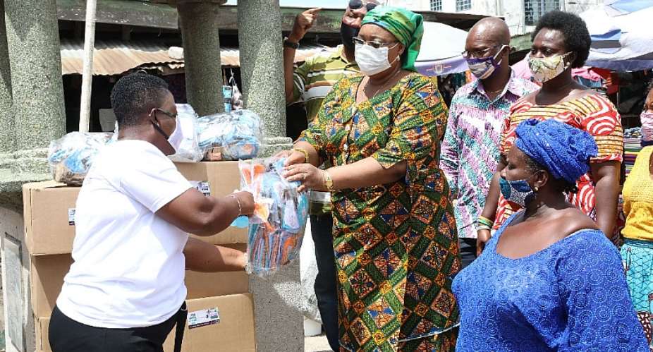 Mrs Amoah presenting the facemask and sanitizers to the market women.