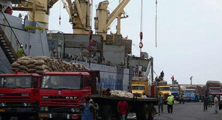 Trucks offloading sacks of raw cocoa beans onto vessels at Tema