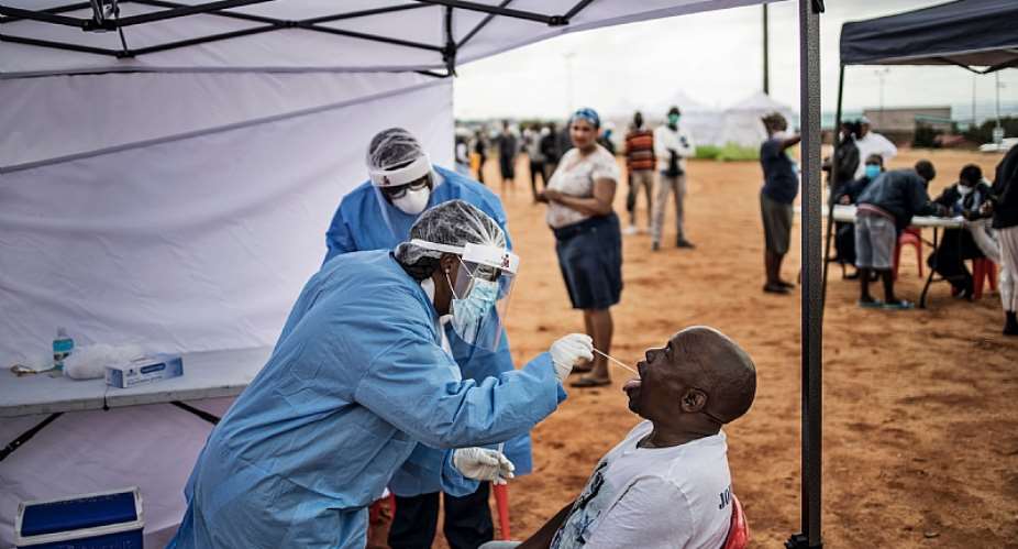 A healthcare worker collecting a swab for a COVID-19 test from a community member.  - Source: AFP via Getty Images