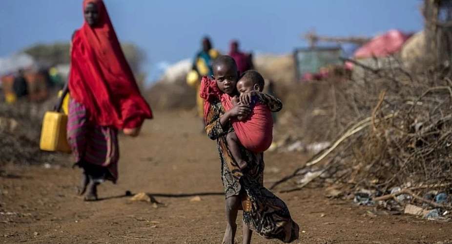 A Somalian girl carries her sibling along land left dry by persistent drought. Getty Image, News24