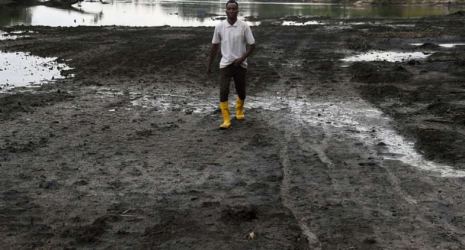 A farmer walks on a marshy shore of a river polluted by oil spills in Nigeria’s Niger delta, region. - Source:
