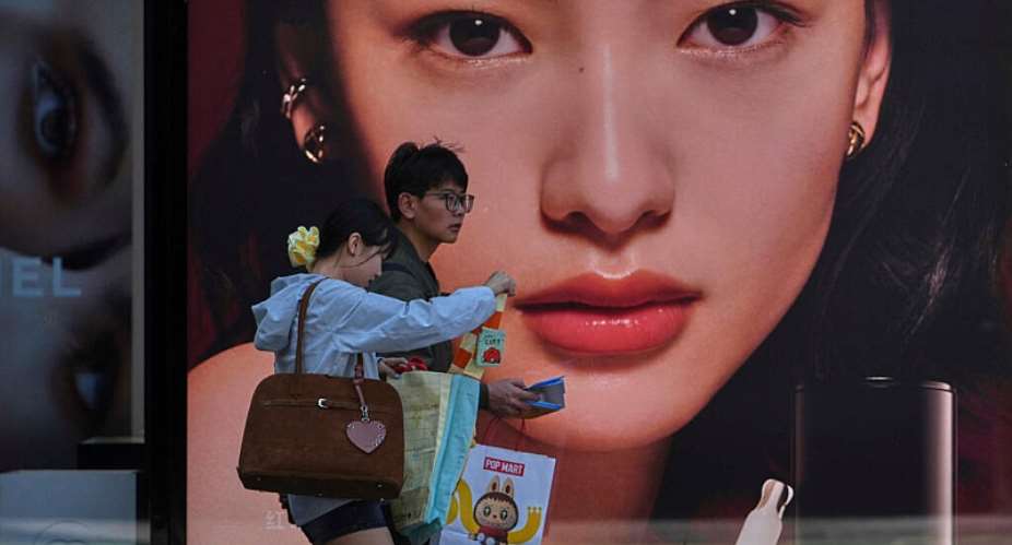 Shoppers with their purchased goods walk by a luxury cosmetic store at an outdoor shopping mall, in Beijing, Monday, April 14, 2025 -  Andy Wong, AP