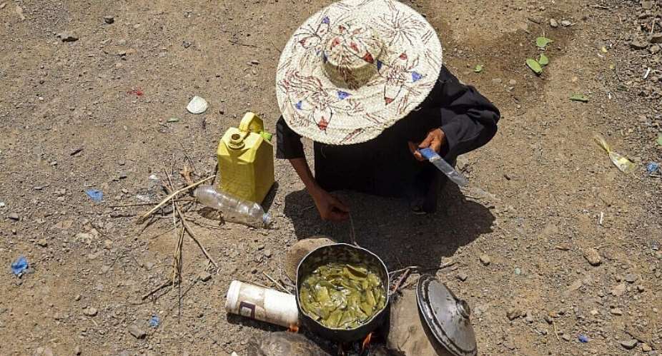 A displaced Yemeni woman boils leaves to feed her grandchildren at the Al-Manij displacement camp near Taez, south-west Yemen, 21 May. - AFP - AHMED AL-BASHA