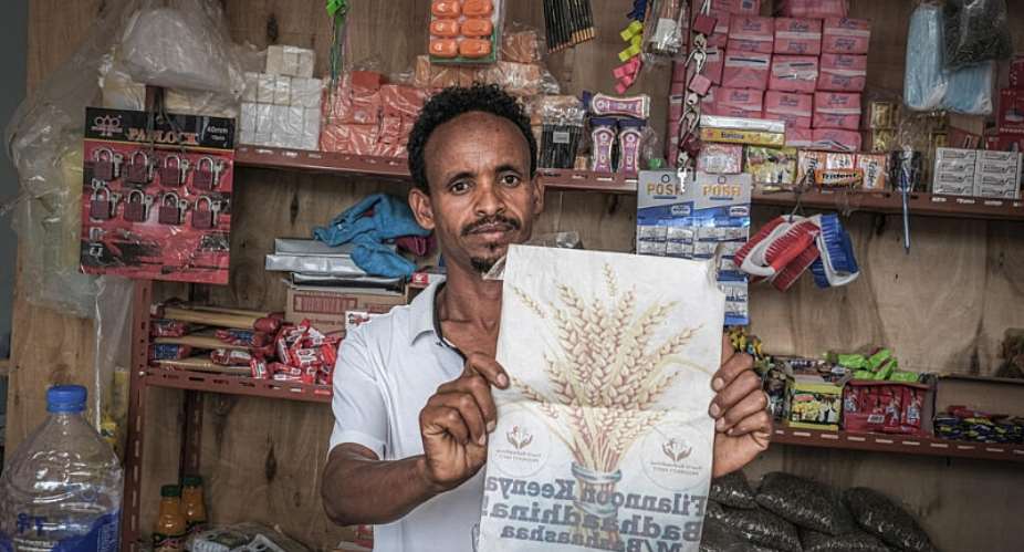 A supporter of Ethiopias ruling Prosperity Party displays a party campaign flyer at his grocery shop in Beshasha, the hometown of Ethiopian Prime Minister Abiy Ahmed, 28 May 2026. - AFP - MARCO SIMONCELLI