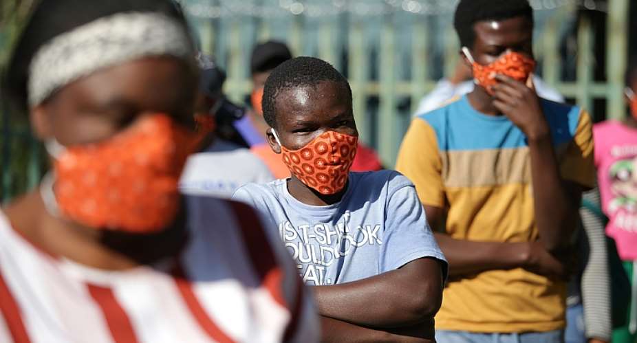 Community members  wearing protective face masks as they queue for aid in Zandspruit informal settlement, north of Johannesburg. - Source: Phill MagakoeAFP via Getty Images