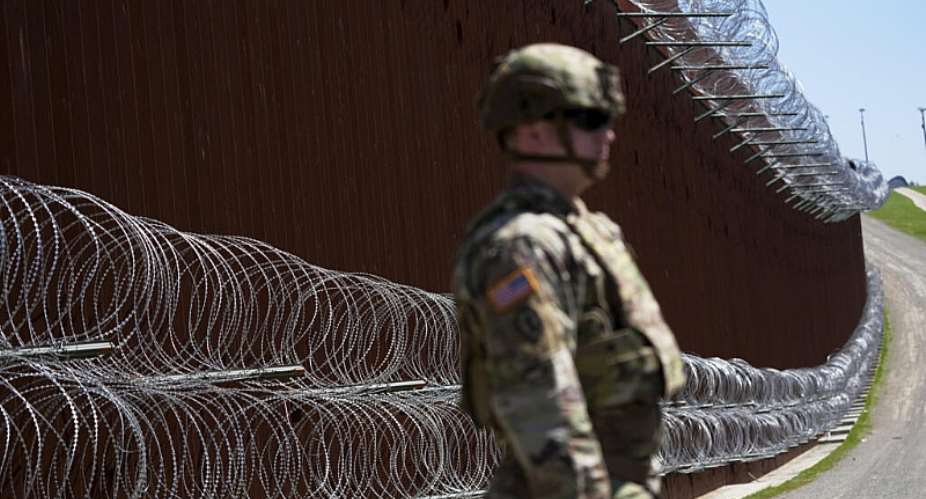 A member of the US military looks on in front of newly-installed concertina wire lining one of two border walls separating Mexico from the United States, March 21, 2025 -  Gregory Bull, AP