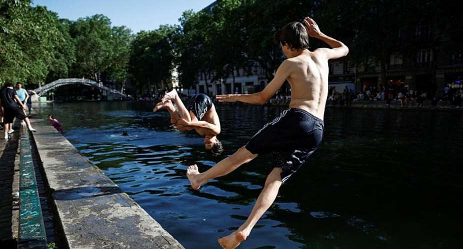 People swim in the Canal Saint-Martin in Paris during an unusually early heatwave, 26 May 2026. - AFP - SIMON WOHLFAHRT