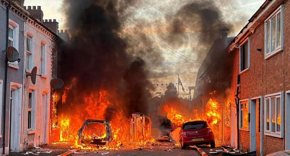 Vehicles set on fire by protesters burn on Lendrick Street in east Belfast, Northern Ireland, on Tuesday, June 9, 2026, after the arrest of a Sudanese man accused of stabbing a man in the northern part of the city. -  PA via AP