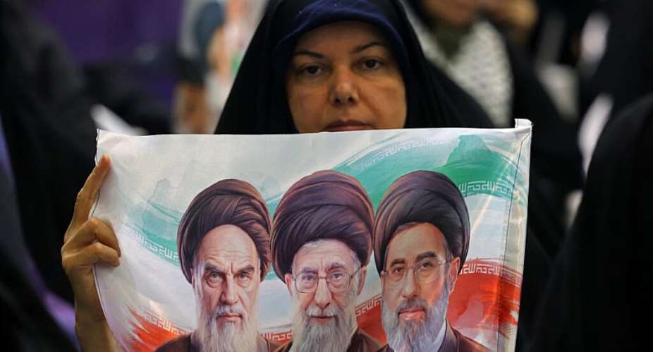 An Iranian woman holds an image of the former and current Iranian supreme leaders in Tehran -  ATTA KENARE, AFP