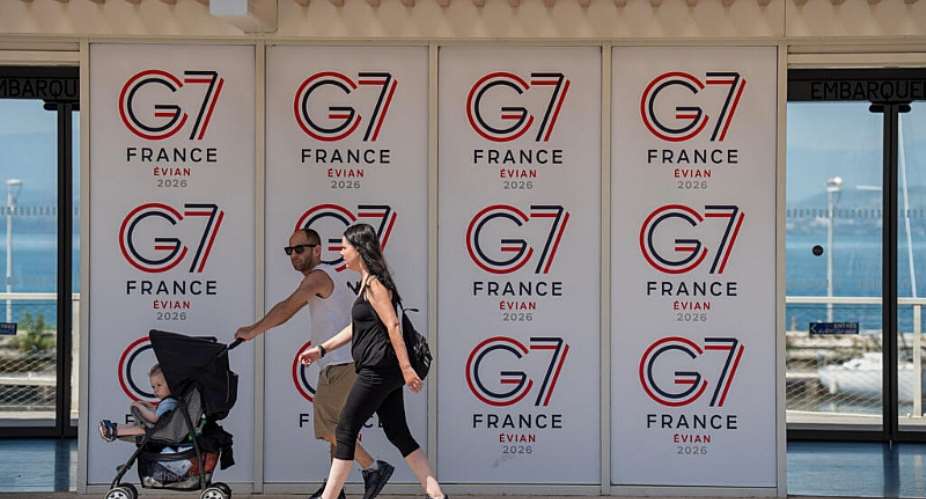 People walk past a G7 banner in Evian-les-Bains, eastern France, Thursday, May 28 , 2026, where the G7 summit is set to take place June 15 - 17/ - AP Photo/Baz Ratner - Baz Ratner