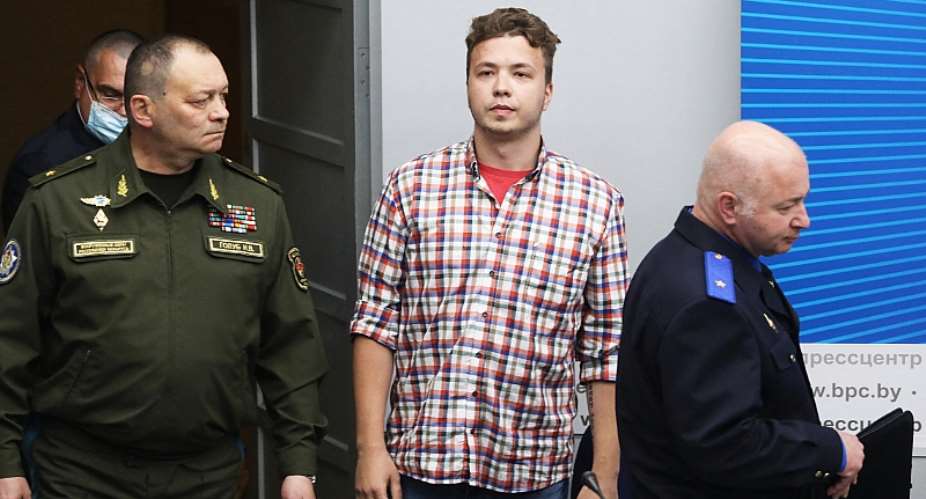 Imprisoned Belarusian journalist Raman Pratasevich is flanked by Belarusian officials as he enters a Ministry of Foreign Affairs-organized press conference in Minsk, Belarus on June 14, 2021. Pratasevich has been forced into several public confessions. AFP