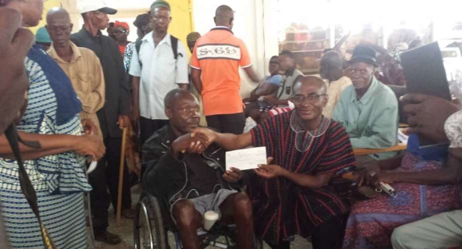 Gerald Atuogya presenting a cheque to a benefiary