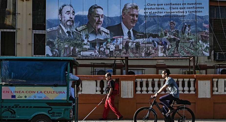 A poster on a street in Havana shows Fidel Castro, his brother Raul Castro, and Cuban President Miguel Daz-Canel on May 20, 2026 -  YAMIL LAGE, AFP