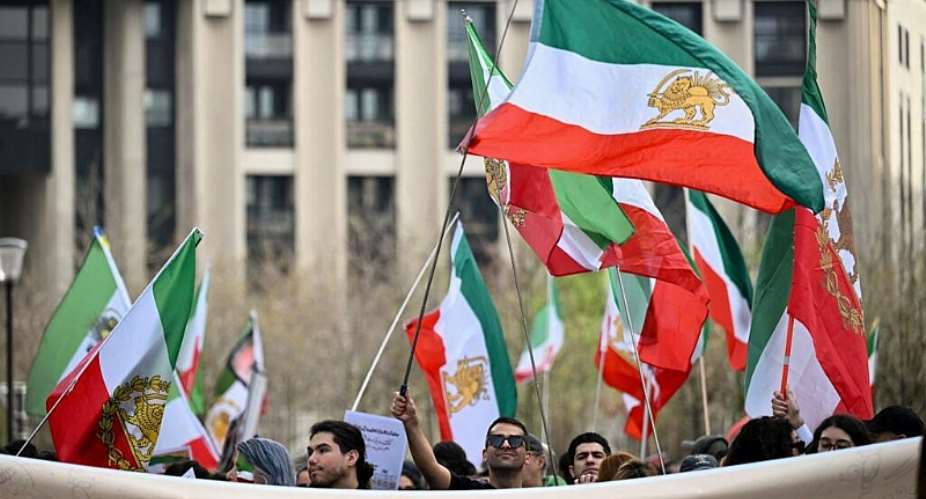 Protesters against the Iranian regime wave Iranian flags from before the 1979 revolution as they gather during a march in Paris on March 7, 2026. -  Lou Benoist, AFP