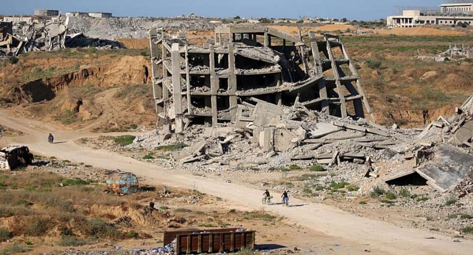 Men ride bicycles past a heavily-damaged building at the Nuseirat camp for Palestinian refugees in the central Gaza Strip on June 19, 2026. -  Eyad Baba, AFP