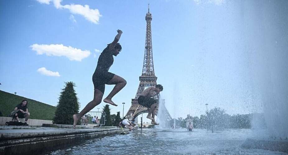 People jump in the Trocadero Fountain near the Eiffel Tower during a heatwave in Paris on 22 June, 2026. - AFP - JULIEN DE ROSA